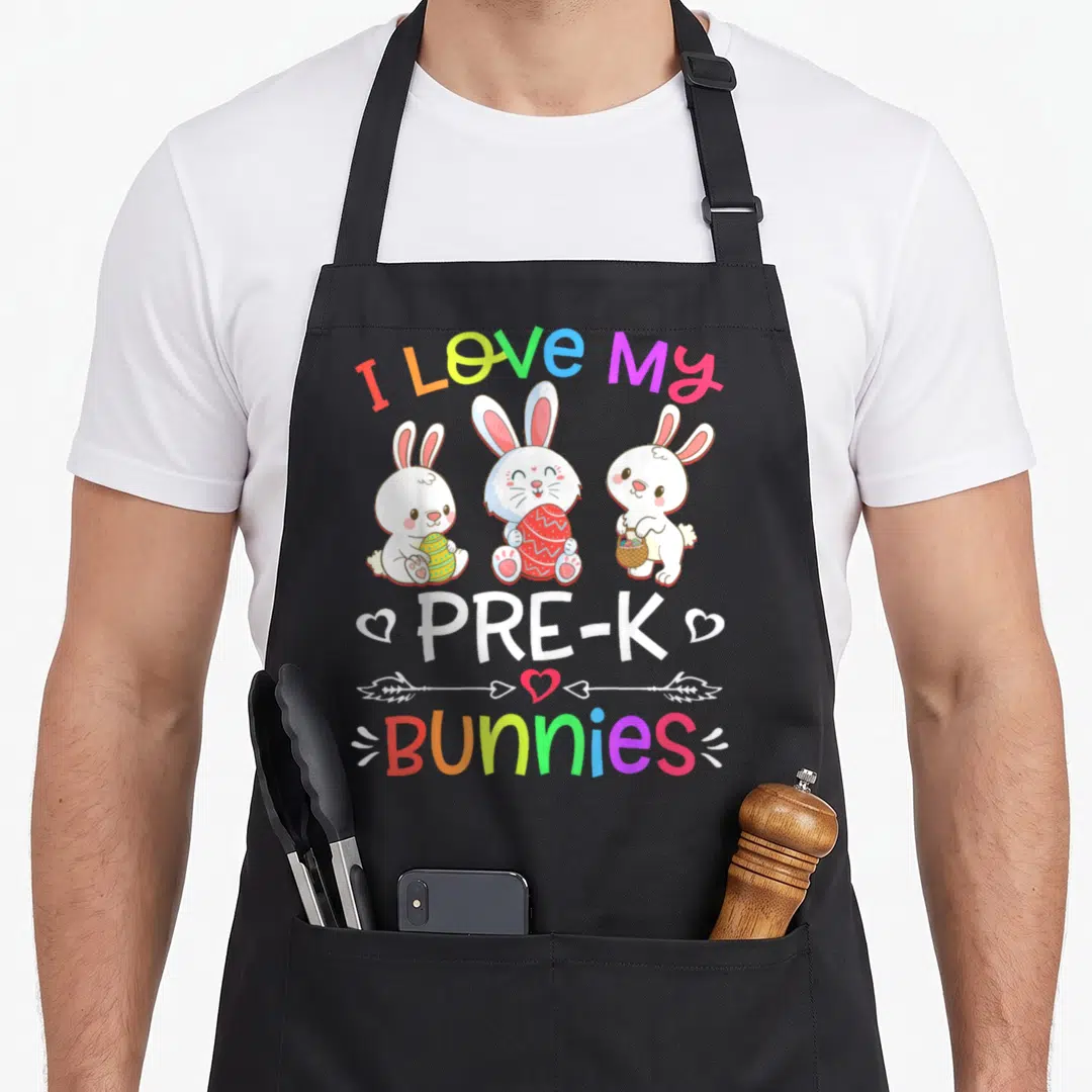 Pre teacher easter bunny aprons - Three cartoon bunnies holding eggs and baskets under rainbow text reading I Love My — shown on a black cotton canvas apron against a white background