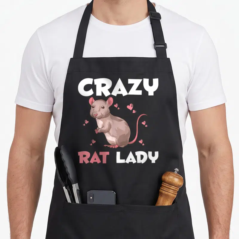 Rat pet animal apron - Cartoon brown rat with pink hearts and CRAZY RAT LADY text — shown on a black cotton canvas apron against a white background