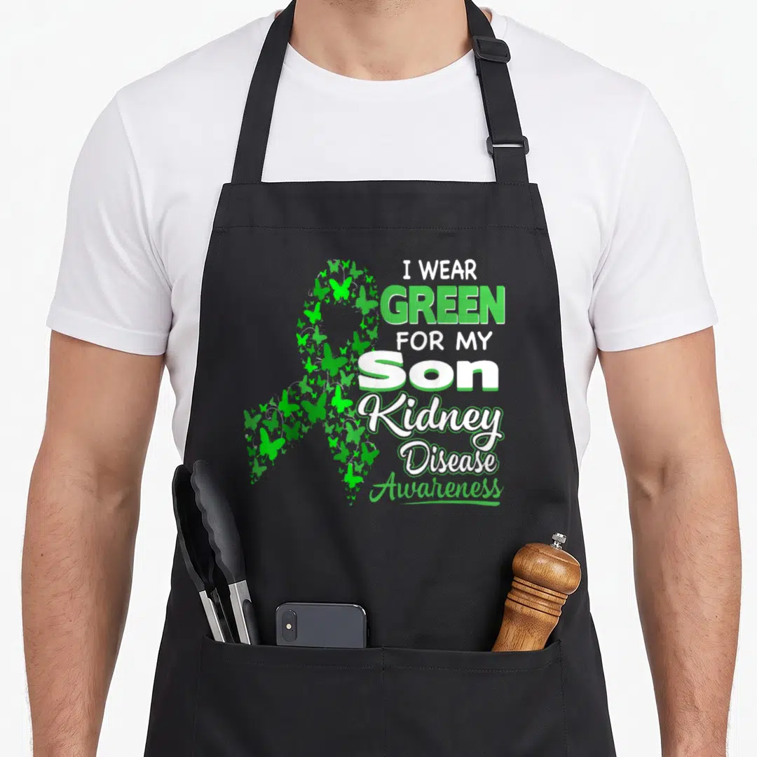Son kidney disease awareness apron - Green and white awareness ribbon made of small butterflies next to stacked text — shown on a black cotton canvas apron against a white background