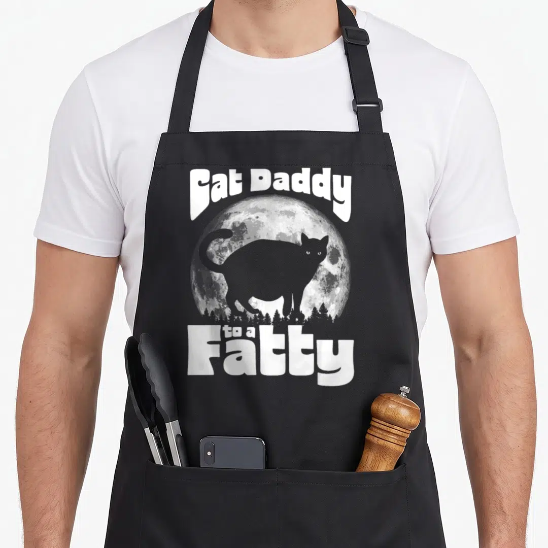 Fatty cat apron - White text Fat Daddy to a Fatty over grey cat silhouette and full moon — shown on a black cotton canvas apron against a white background