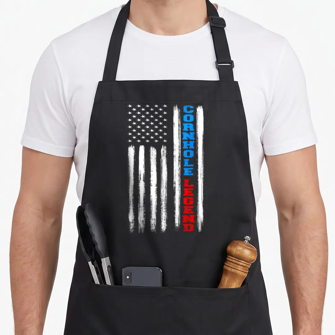 Cornhole american flag apron - Distressed USA flag with vertical blue CORNHOLE and red LEGEND text on black fabric — shown on a black cotton canvas apron against a white background