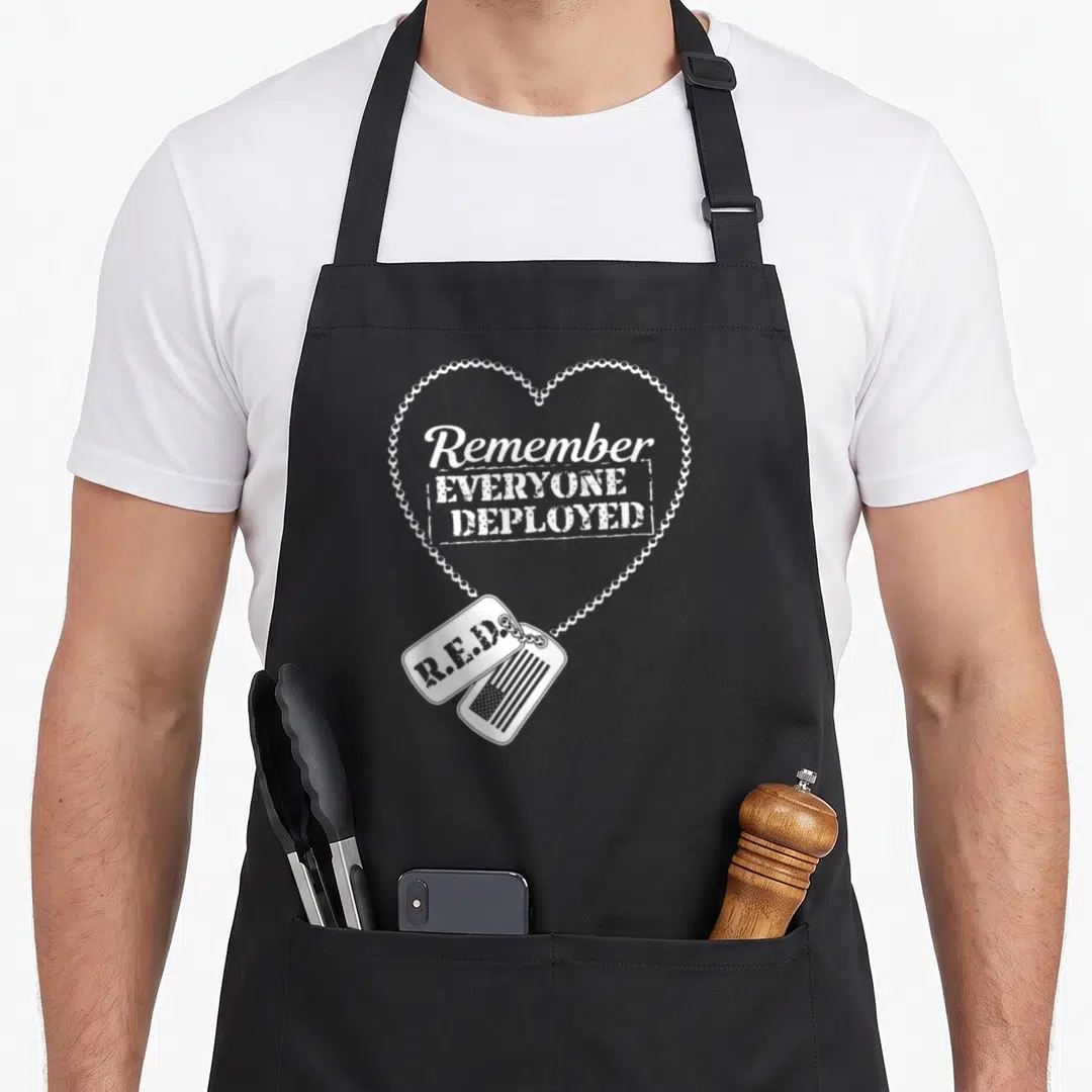 Friday e.a apron - White distressed dog tags and heart chain with Remember Everyone Deployed text — shown on a black cotton canvas apron against a white background