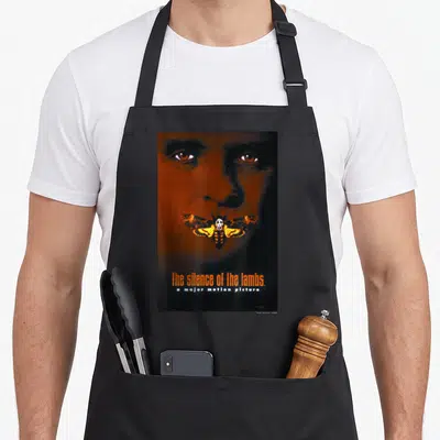 Silence moth collecting apron - Orange and black face portrait with skull-winged moth and stacked movie title text — shown on a black cotton canvas apron against a white background