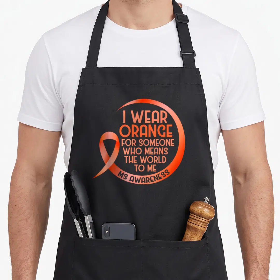 Someone msemen apron - Orange awareness ribbon overlapping a circular arc with stacked text reading I Wear Orange — shown on a black cotton canvas apron against a white background