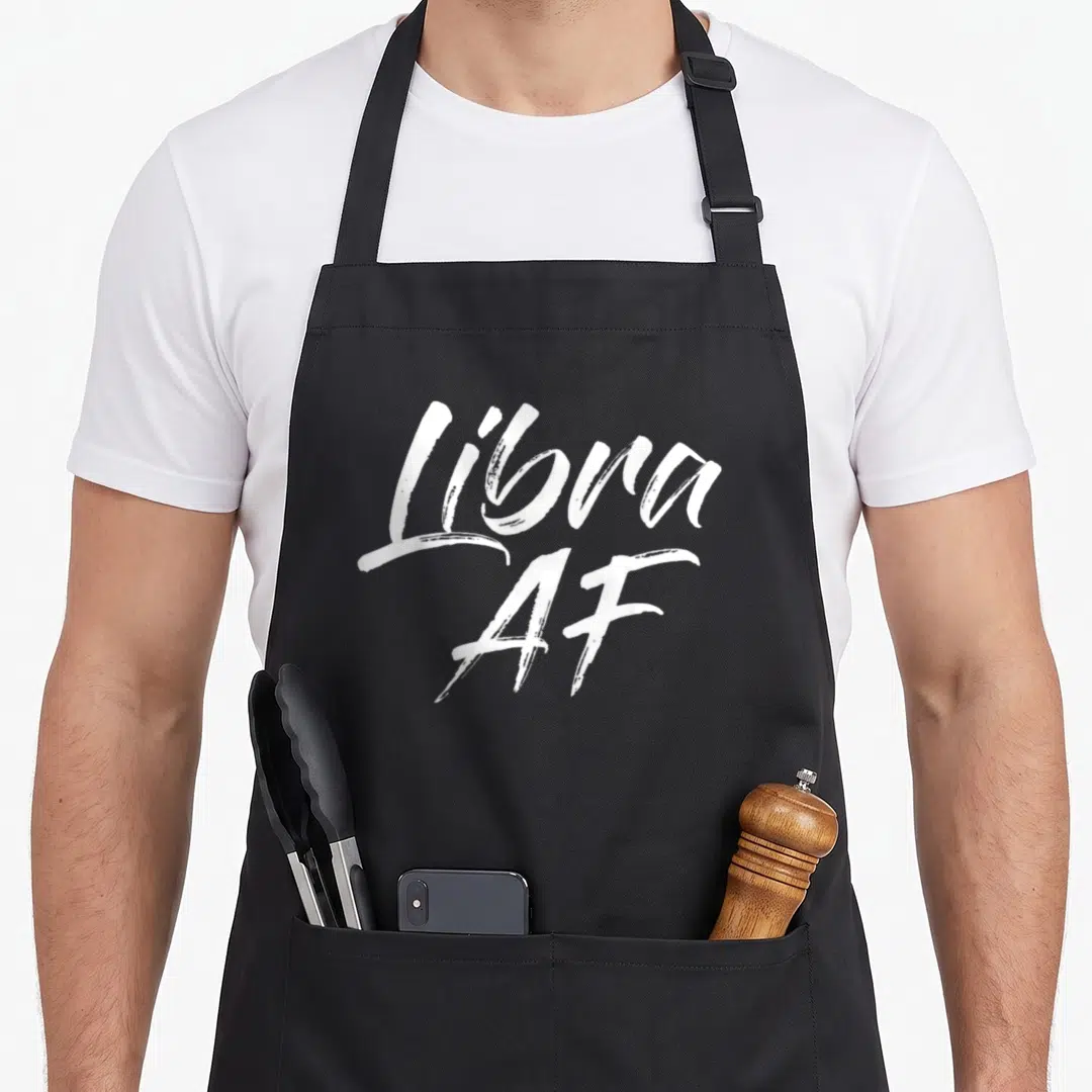 Funny libra apron - White brush script text reading Libra AF on grey background — shown on a black cotton canvas apron against a white background