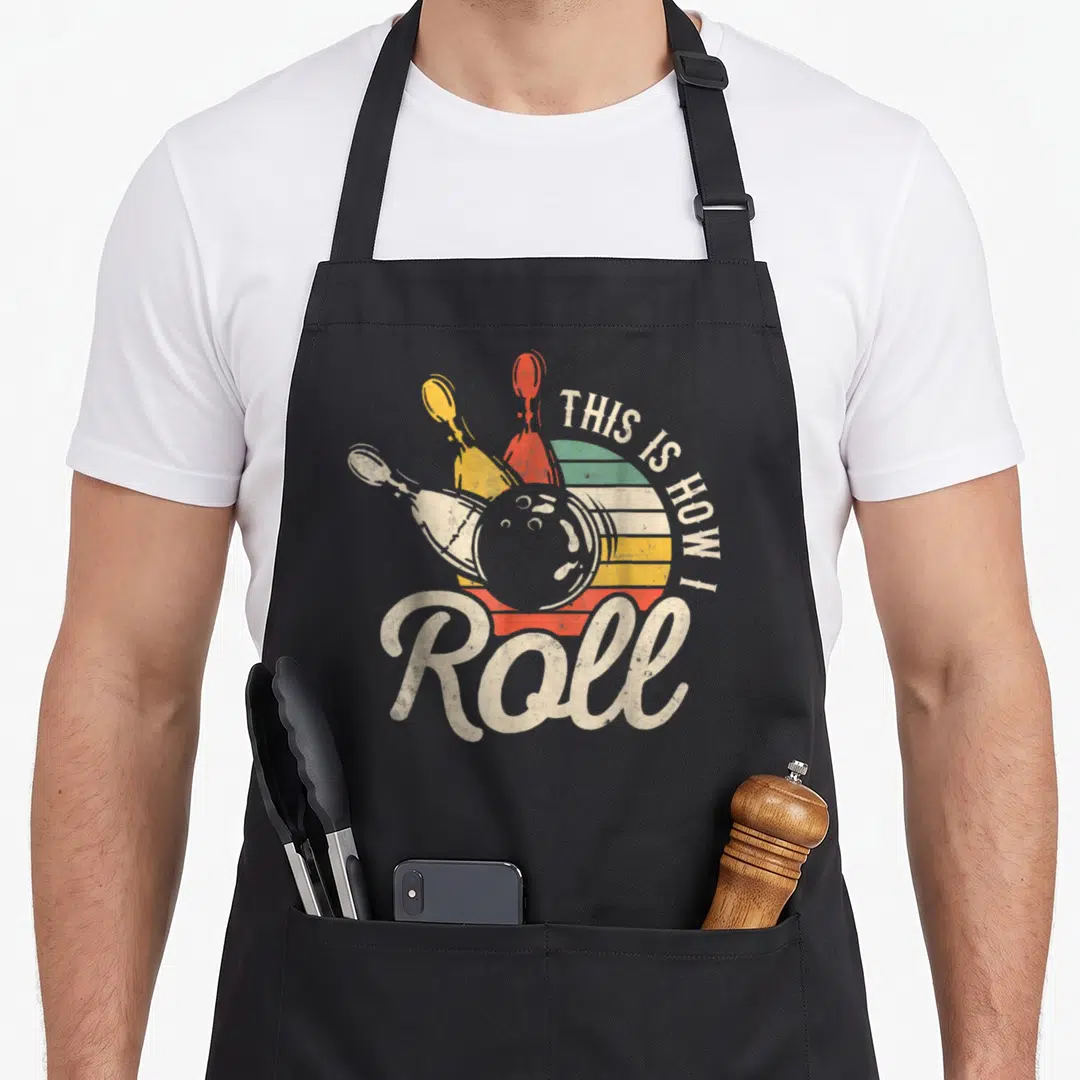 Roll retro bowling apron - Retro bowling ball and pins over striped semi-circle with arched text — shown on a black cotton canvas apron against a white background