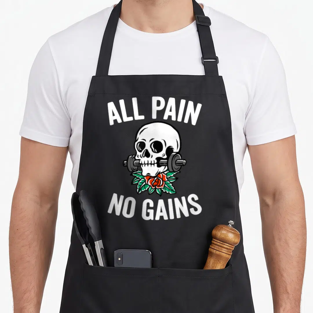 Gym round neck apron - Skull biting barbell with red rose and ALL PAIN NO GAINS text — shown on a black cotton canvas apron against a white background