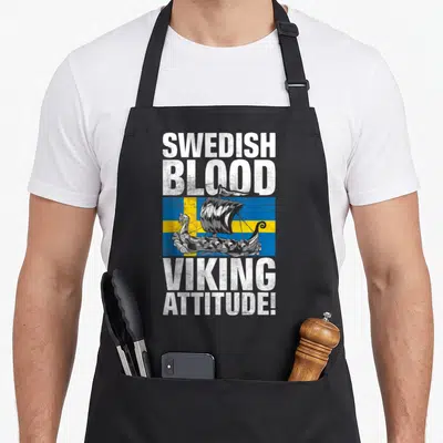 Blood swedish apron - Viking ship on Swedish flag with stacked SWEDISH BLOOD VIKING ATTITUDE text in distressed white — shown on a black cotton canvas apron against a white background