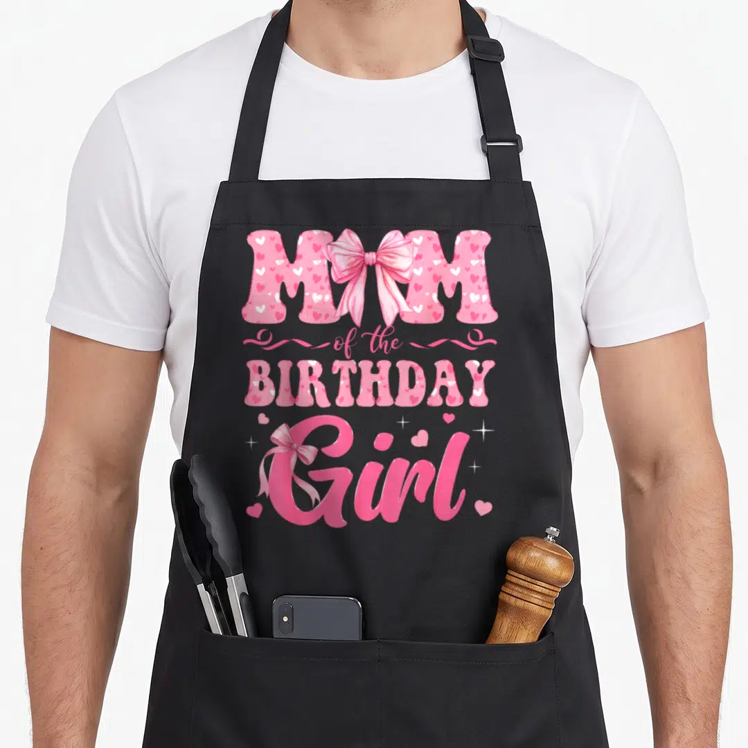 Coquette family bow apron - Pink and white typography reading MOM of the BIRTHDAY Girl with heart patterns and ribbon — shown on a black cotton canvas apron against a white background