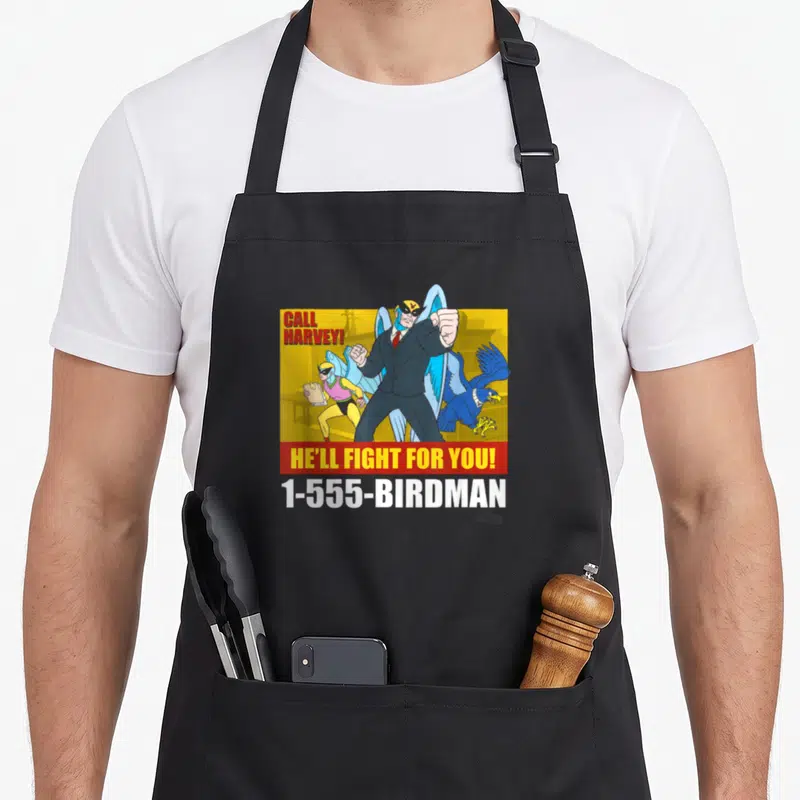 Harvey attorney apron - Winged superhero in suit with CALL HARVEY text and phone number on yellow background — shown on a black cotton canvas apron against a white background