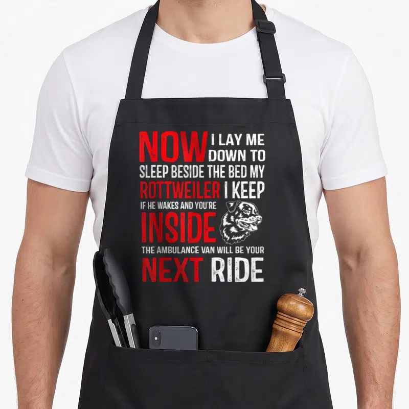 Cute rottweiler dog apron - Stacked red and white text with Rottweiler head illustration and sarcasm quote — shown on a black cotton canvas apron against a white background