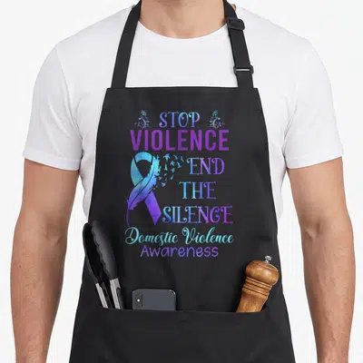 Family domestic aprons - Purple blue awareness ribbon with flying birds and text Stop Violence End The Silence — shown on a black cotton canvas apron against a white background