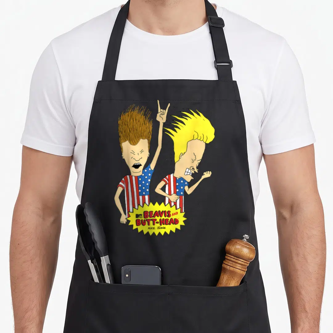 Beavis us aprons - Two cartoons in flag shirts with yellow burst logo reading Beavis and Butt-Head Mike Judge — shown on a black cotton canvas apron against a white background