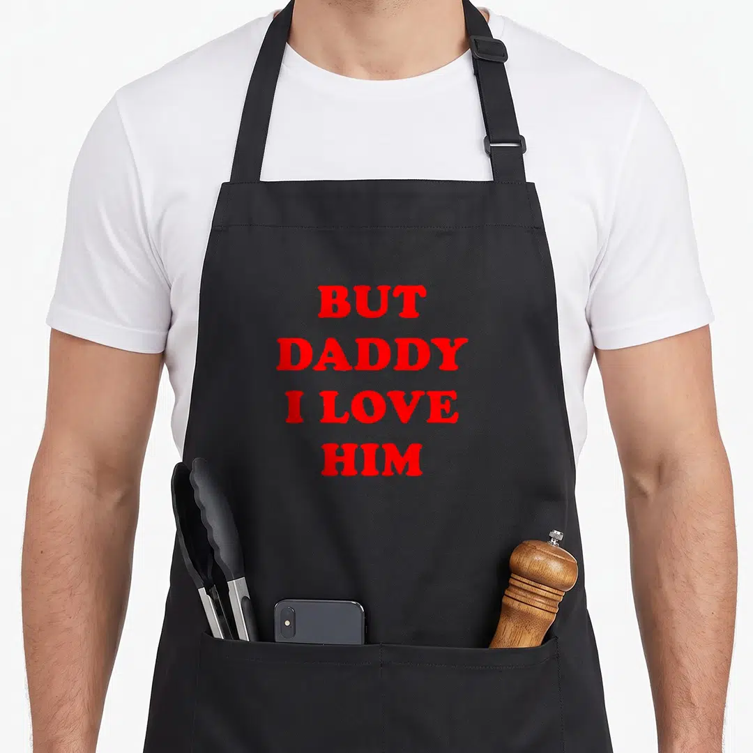 But daddy apron - Red stacked text reading BUT DADDY I LOVE HIM on grey background — shown on a black cotton canvas apron against a white background
