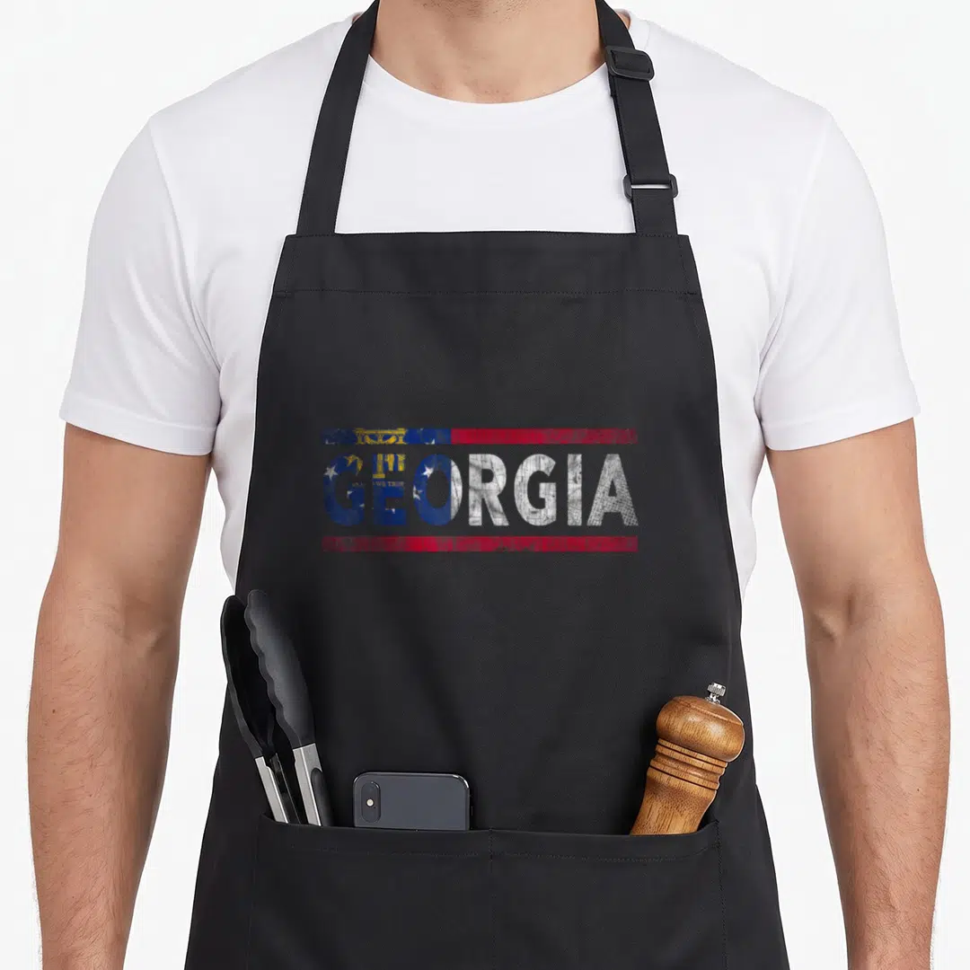 Georgia distressed apron - Stacked GEORGIA text filled with distressed blue red and white flag pattern — shown on a black cotton canvas apron against a white background