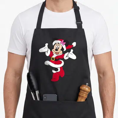 Cute holiday santa apron - Minnie Mouse in red Santa suit with pink bow and white trim centered on black apron — shown on a black cotton canvas apron against a white background
