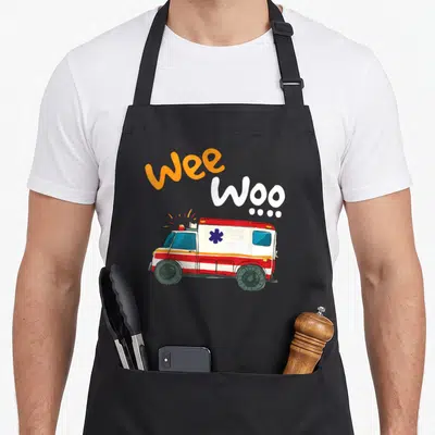 Paramedic ambulance apron - Cartoon ambulance with red stripes and wee Woo text in orange and white — shown on a black cotton canvas apron against a white background