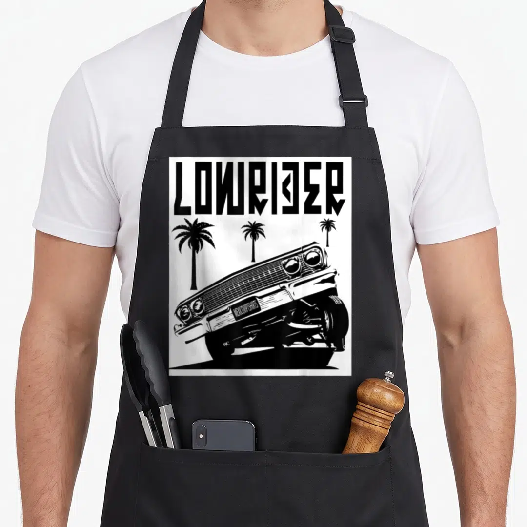 Mexicoviptshirt crew apron - Black and white lowrider car graphic with three palm trees and bold text — shown on a black cotton canvas apron against a white background