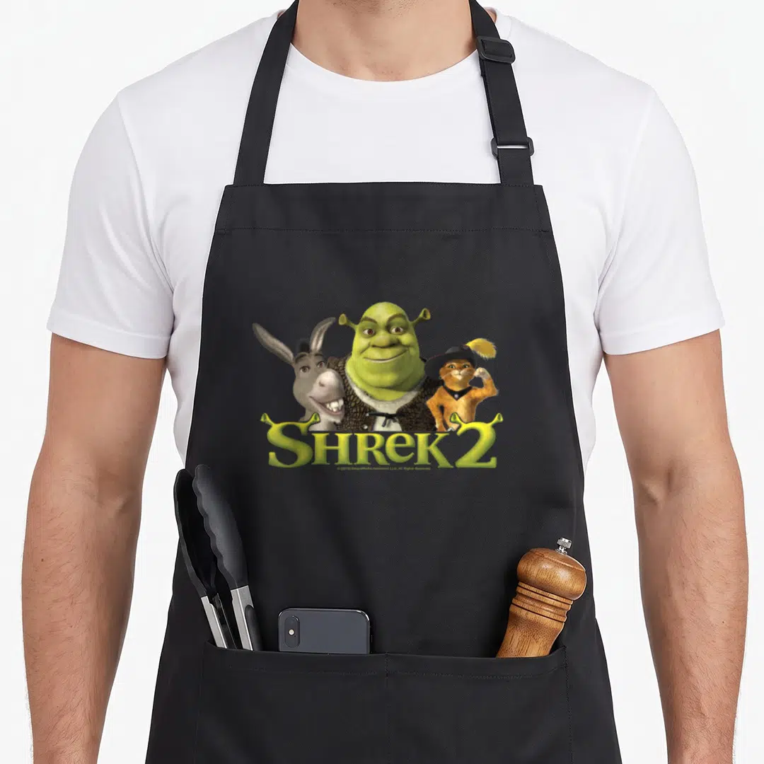 Donkey friends apron - Shrek Donkey Puss in Boots photo print with yellow SHREK 2 text below — shown on a black cotton canvas apron against a white background
