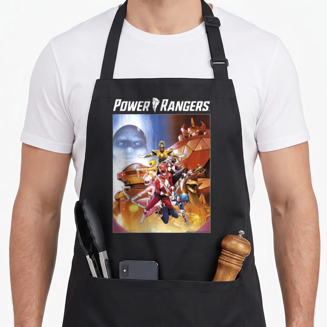 Action rainbow apron - Power Rangers logo above rangers in red, blue, yellow, white, and gold posing with weapons near — shown on a black cotton canvas apron against a white background