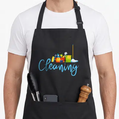 Funny cleaning housekeeper apron - Cartoon red and green buckets filled with brushes, yellow gloves, soap, and a mop — shown on a black cotton canvas apron against a white background