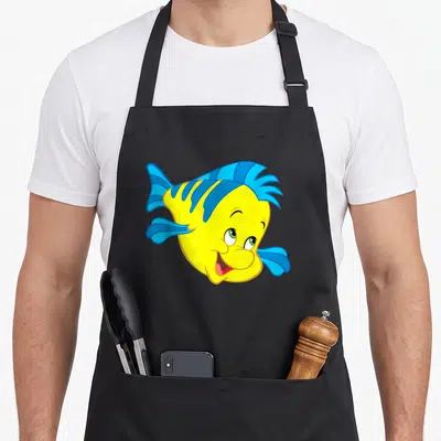Sidekick face apron - Cartoon fish head in yellow and blue with a wide smile — shown on a black cotton canvas apron against a white background