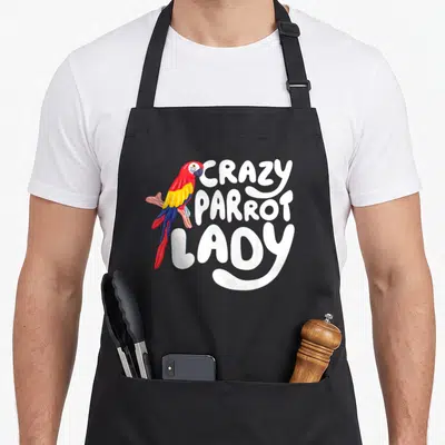 Pet owner bird apron - Cartoon parrot perched on branch beside white text reading CRAZY PARROT LADY — shown on a black cotton canvas apron against a white background