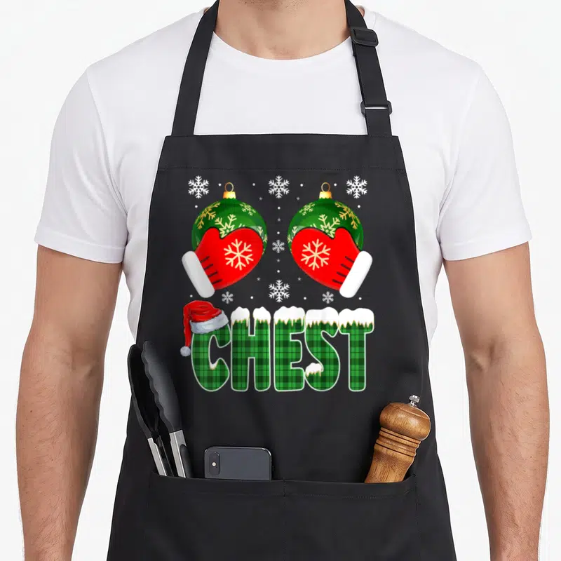 Chestnut chest family christmas aprons - Two red mittens holding green ornaments above plaid CHEST text with Santa hat — shown on a black cotton canvas apron against a white background