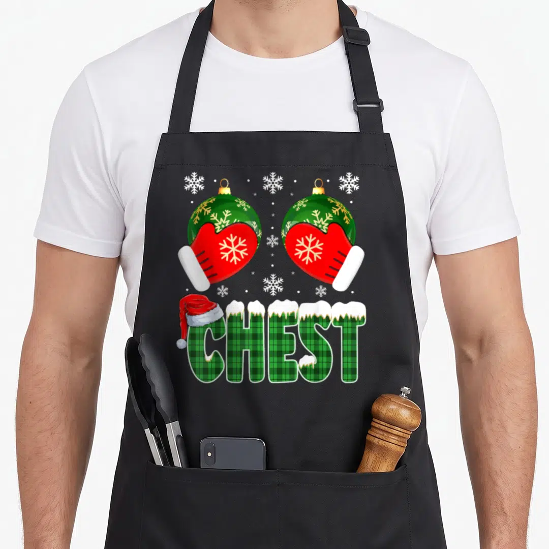 Chestnut chest family christmas aprons - Two red mittens holding green ornaments above plaid CHEST text with Santa hat — shown on a black cotton canvas apron against a white background