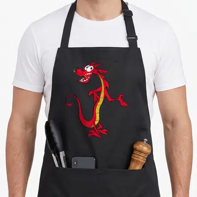 Mushu dragon apron - Red cartoon dragon with yellow belly standing upright with open mouth — shown on a black cotton canvas apron against a white background