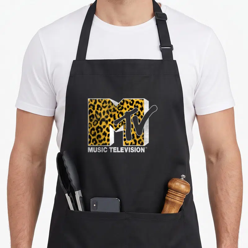 Mtv cheetah apron - Retro MTV logo with yellow black cheetah print and MUSIC TELEVISION text below — shown on a black cotton canvas apron against a white background