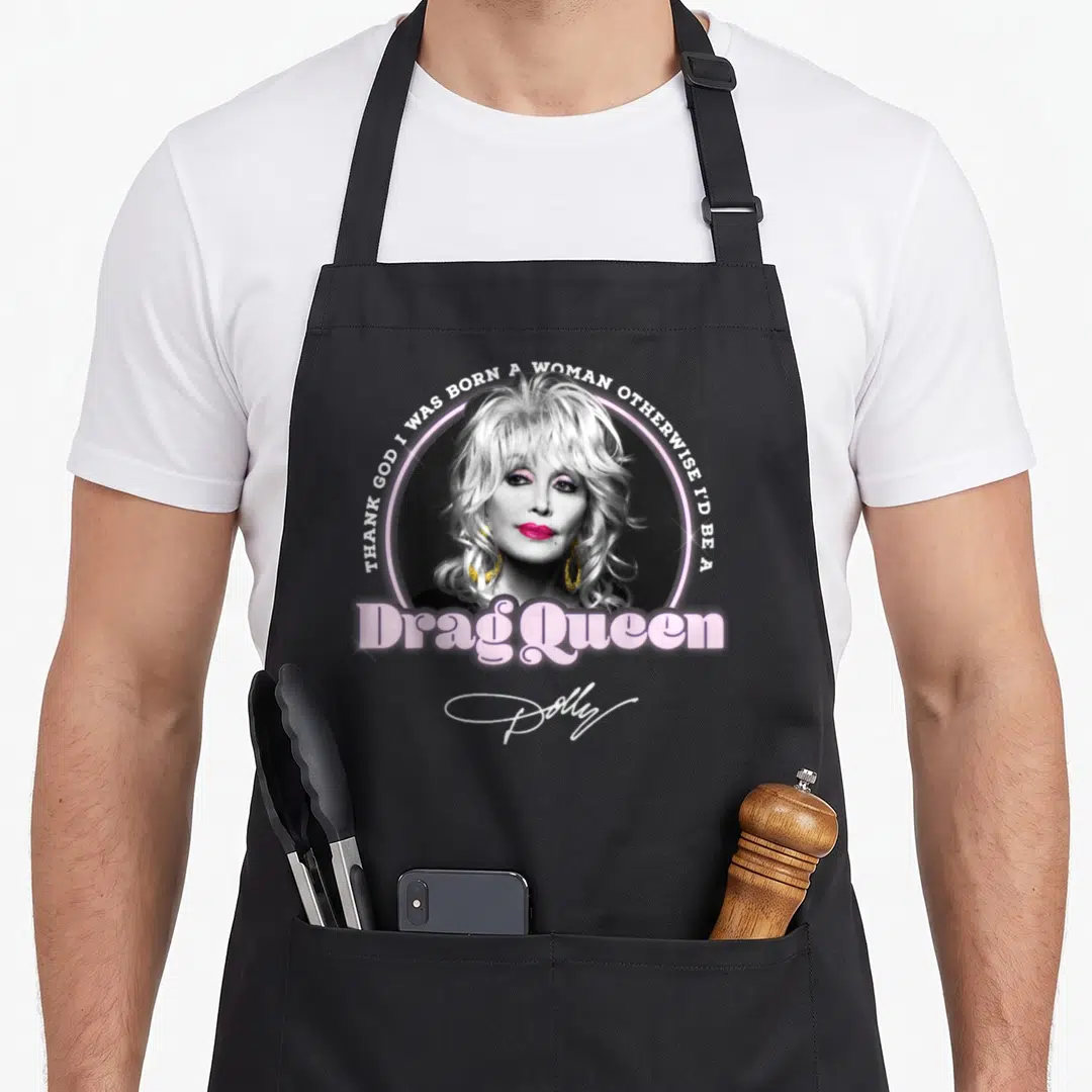 Drag dolly parton apron - Dolly Parton photo in pink circle with drag queen text and signature — shown on a black cotton canvas apron against a white background
