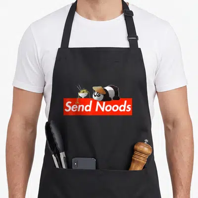 Nood pho apron - Cartoon panda with hat and noodle bowl above red banner reading Send Noods — shown on a black cotton canvas apron against a white background