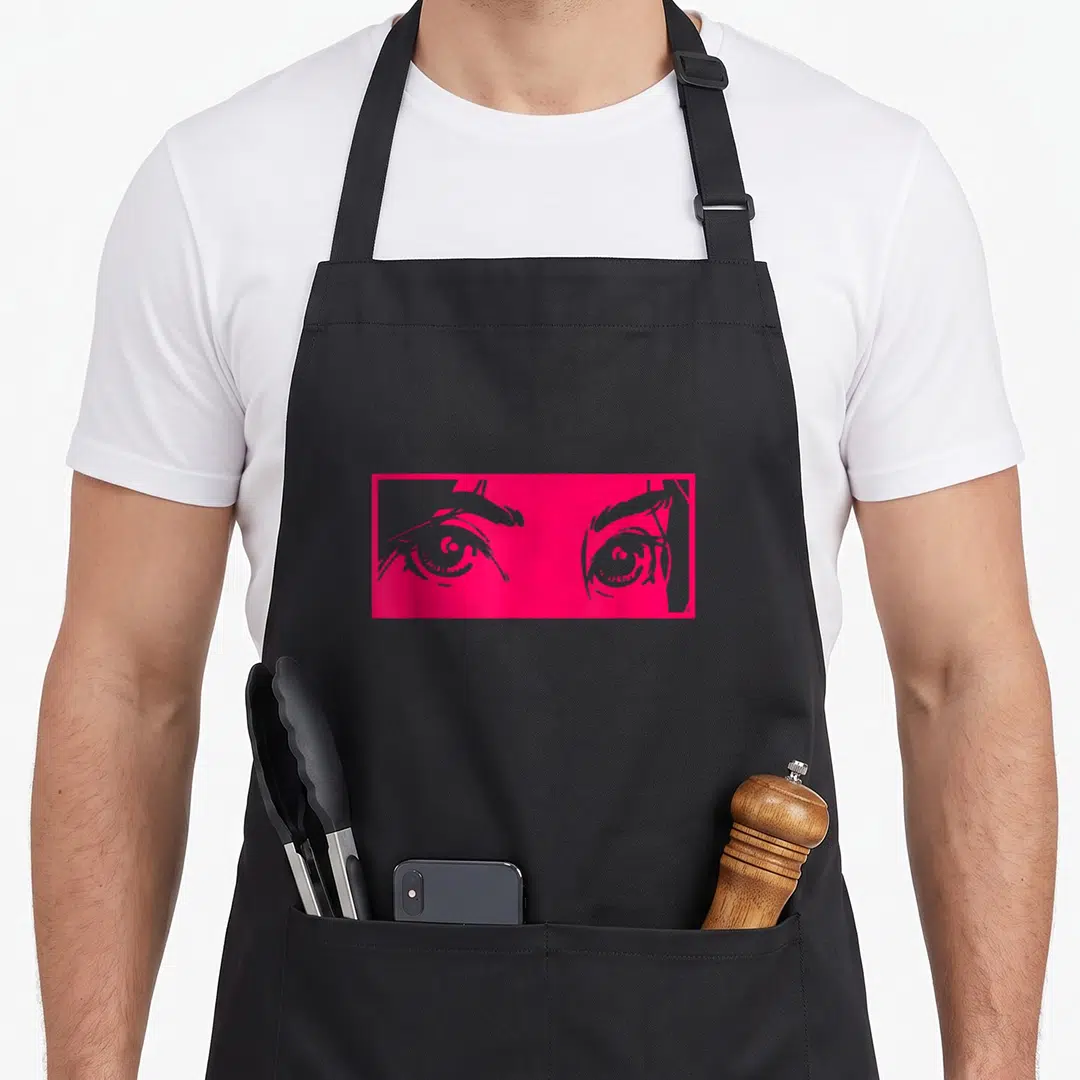80s japan apron - Pink rectangle with two stylized eyes and grey finger details — shown on a black cotton canvas apron against a white background