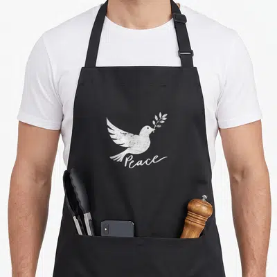 Dove peace sign apron - White distressed dove holding an olive branch with script text Peace below — shown on a black cotton canvas apron against a white background
