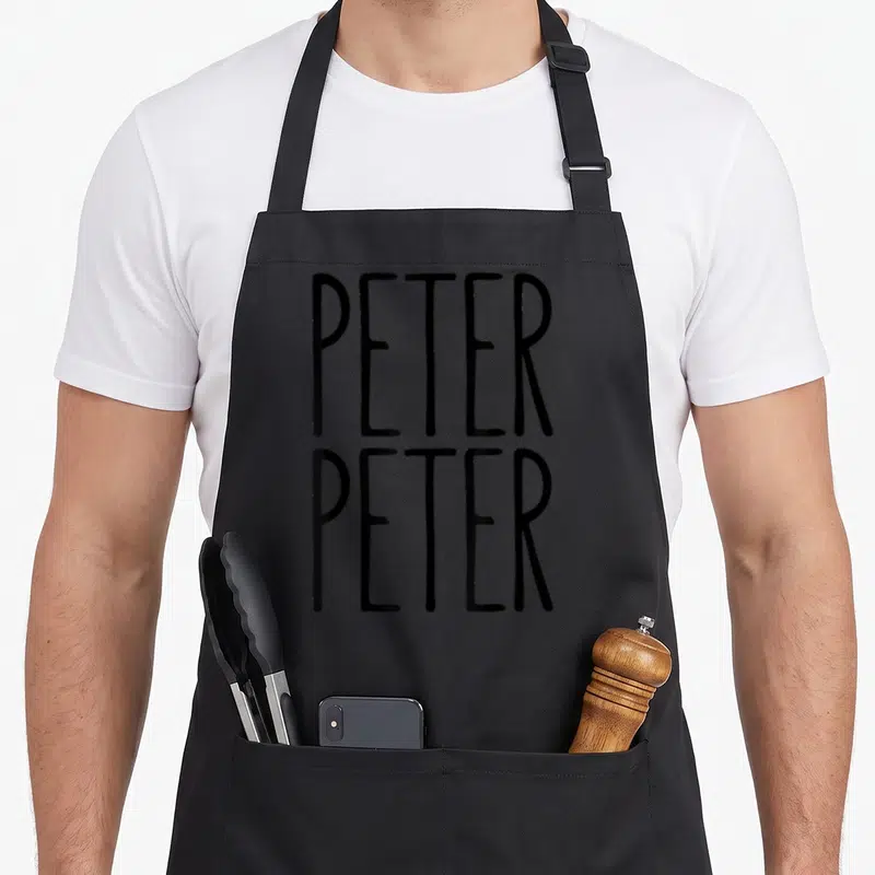 Eater costume pumpkin apron - Black stacked PETER PETER typography on plain background — shown on a black cotton canvas apron against a white background