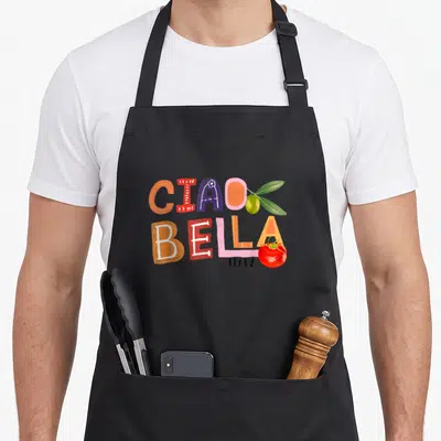 Garden italian apron - Ciao Bella Italy text with olive and tomato in orange purple pink red cartoon style — shown on a black cotton canvas apron against a white background