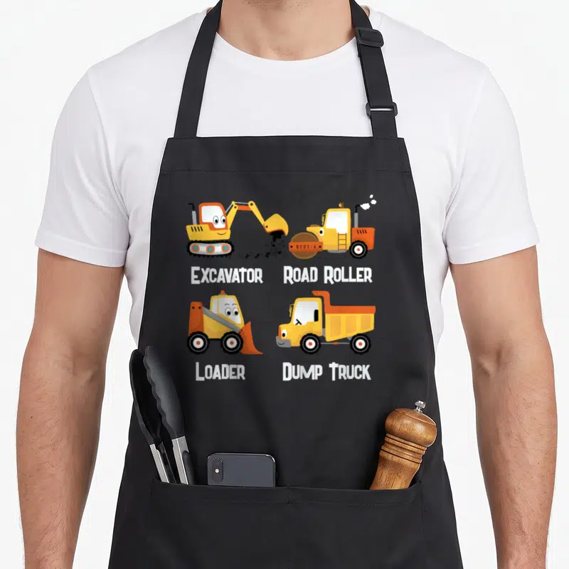 Toddler dump truck apron - Four cartoon construction vehicles labeled Excavator Road Roller Loader Dump Truck in yellow — shown on a black cotton canvas apron against a white background