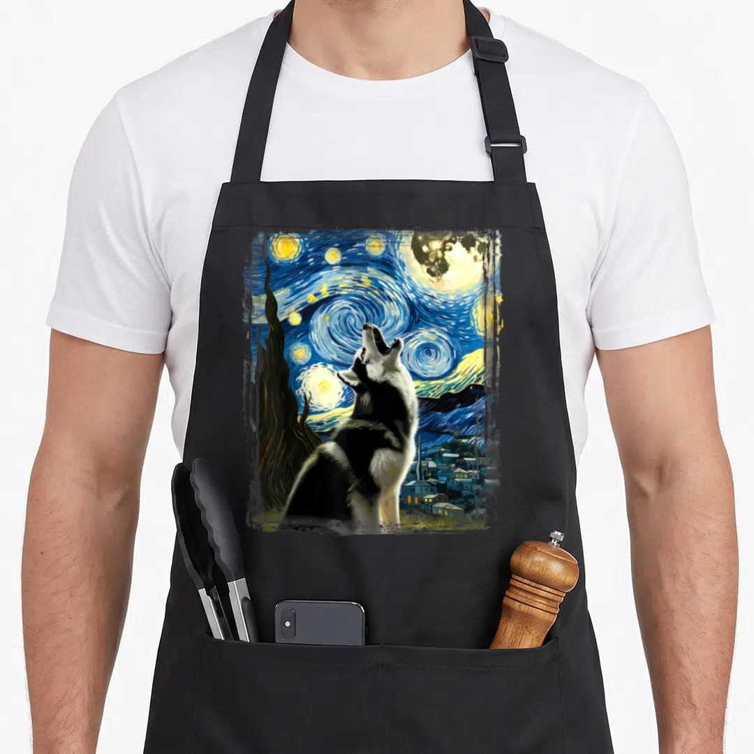 Van husky apron - Husky howling at swirling blue and yellow starry night sky with cypress tree and village — shown on a black cotton canvas apron against a white background