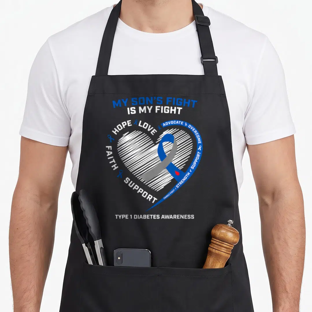 T1d dad and son aprons - White sketched heart with blue ribbon and red drop surrounded by advocacy words — shown on a black cotton canvas apron against a white background