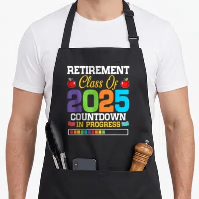 Class countdown teacher apron - Retirement Class Of 2025 Countdown In Progress text with colorful apples and books — shown on a black cotton canvas apron against a white background