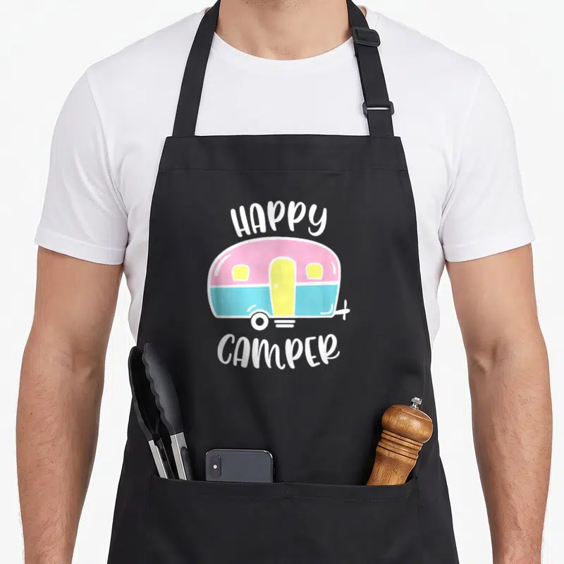 Decor trailer apron - Pink blue and yellow cartoon camper illustration with white HAPPY CAMPER text — shown on a black cotton canvas apron against a white background