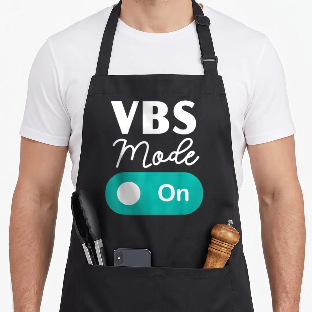 Bible teacher apron - Stacked VBS Mode On text above teal toggle switch graphic — shown on a black cotton canvas apron against a white background
