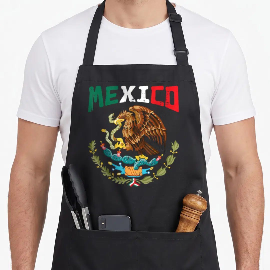 Independence mexico mexican apron - MEXICO text in green white red above brown eagle perched on cactus with snake — shown on a black cotton canvas apron against a white background