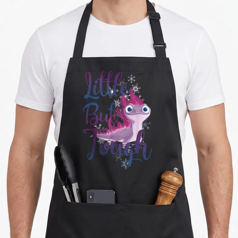But frozen apron - Purple salamander with pink flames and Little But Tough text surrounded by snowflakes — shown on a black cotton canvas apron against a white background