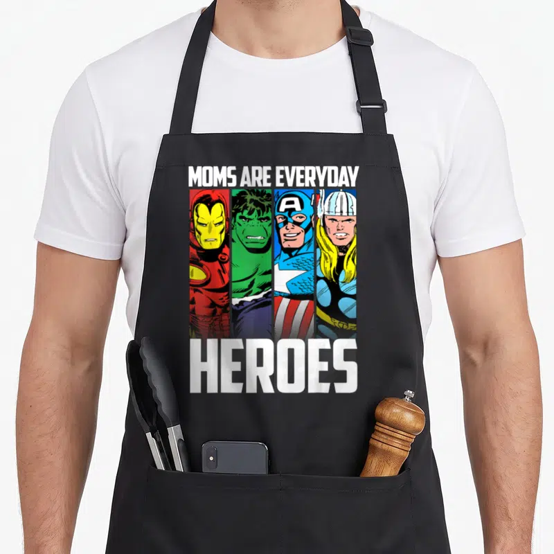 Everyday mother's day aprons - MOMS ARE EVERYDAY HEROES text above four vertical cartoon superhero portraits in red — shown on a black cotton canvas apron against a white background