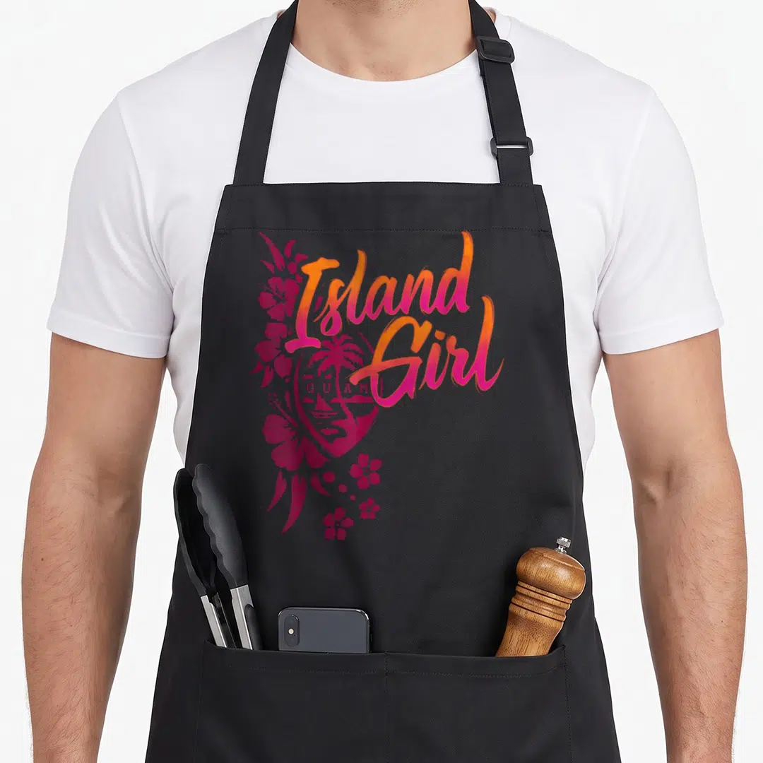 Flower guam aprons - Island Girl GUAM text over heart with palm tree, sailboat, and pink hibiscus flowers — shown on a black cotton canvas apron against a white background