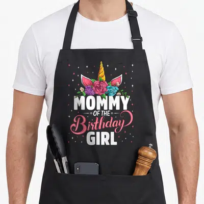 Unicorn family aprons - MOMMY OF THE Birthday GIRL text below unicorn horn, ears, and colorful roses with stars — shown on a black cotton canvas apron against a white background