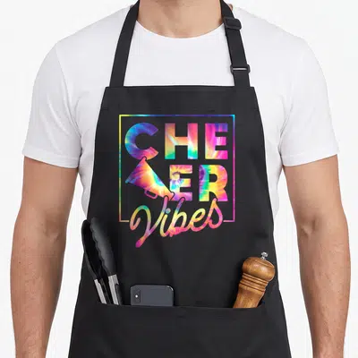 Cheerleader crew apron - Tie-dye CHEER Vibes text with megaphone in C, bordered design on black — shown on a black cotton canvas apron against a white background