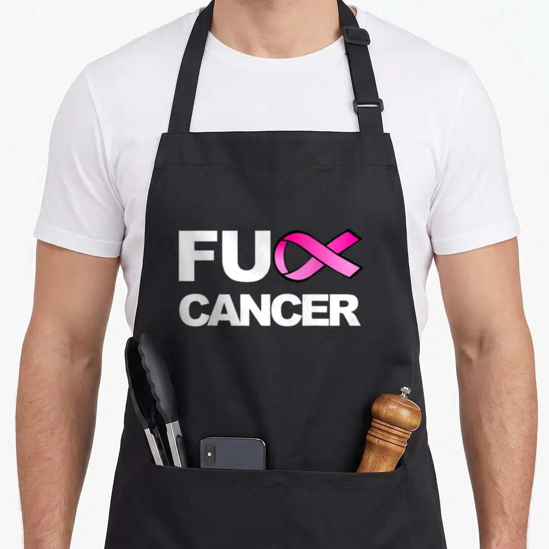 Cute breast cancer awareness aprons - FUC CANCER text with pink ribbon replacing K in white and pink typography — shown on a black cotton canvas apron against a white background